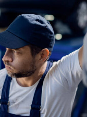 Auto mechanic feeling displeased about something while working at repair shop.